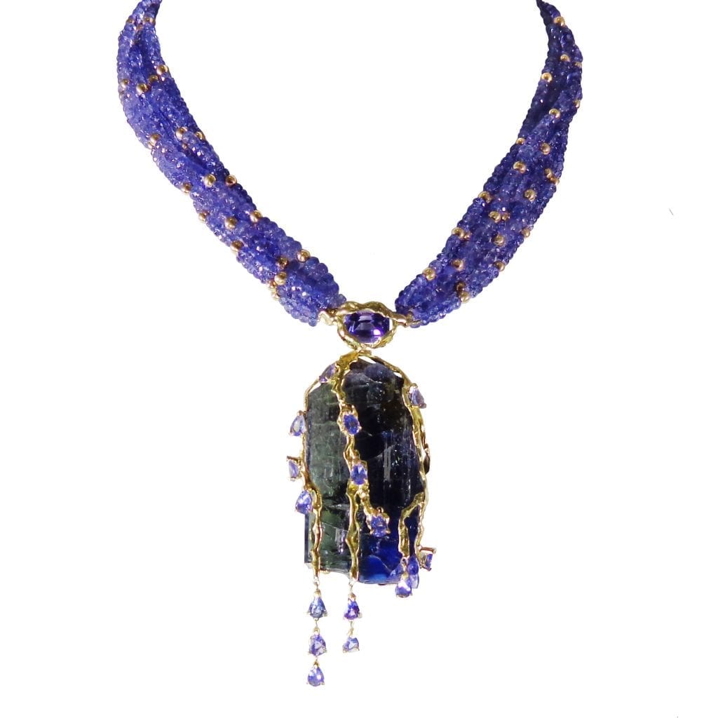 Collier multirangs de disques de Tanzanite facettées entrecoupées de boules d'or. Pendentif avec un brut de Tanzanite tranché, rehaussé d'or jaune granité 18k, accompagné de poires de Tanzanites facettées. Fermoir en or jaune 18K